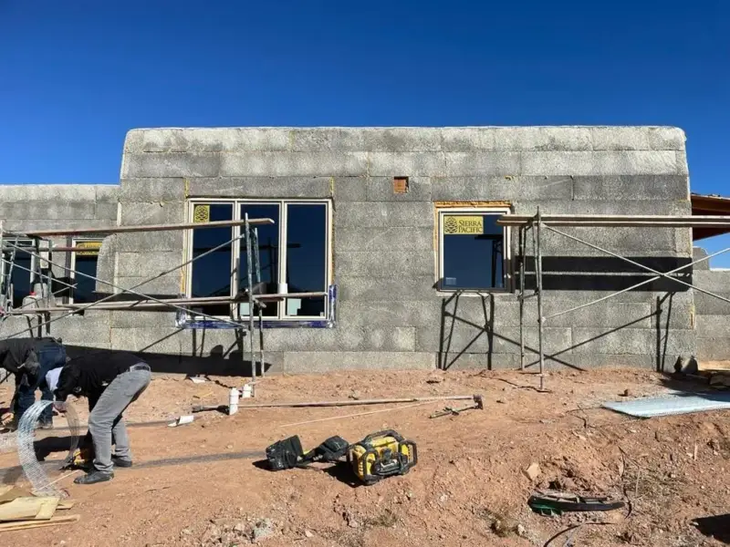 Bare concrete block house with scaffolding before stucco
