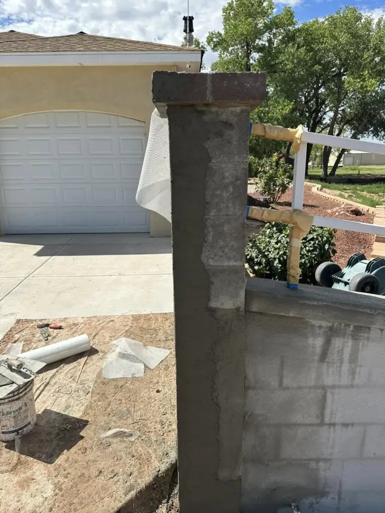 Concrete block pillar covered in a stucco brown coat with trim formed at the top