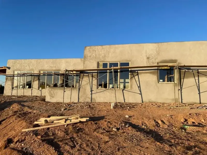 Flat-roof block house with a new stucco brown coat and scaffolding across the front