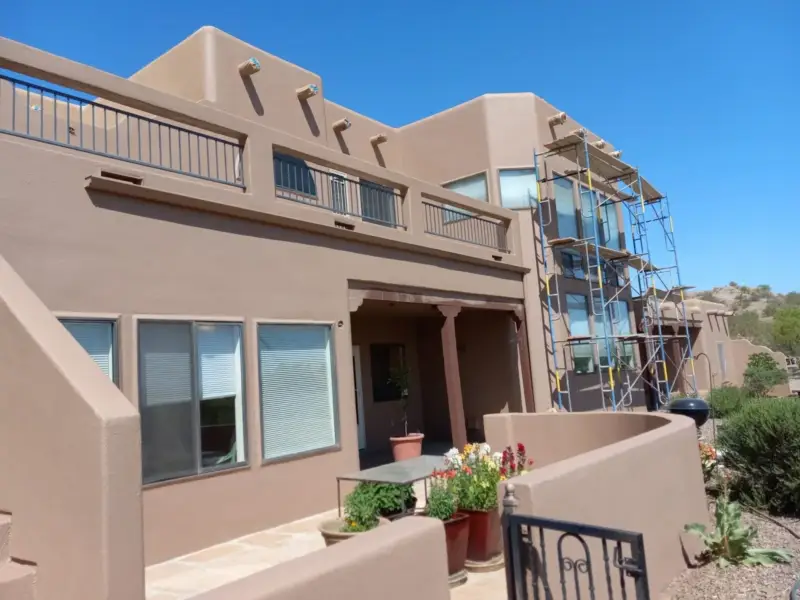 Two-story Pueblo style stucco home with scaffolding set up for coating