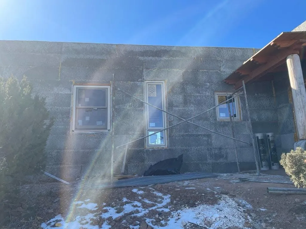 Side wall of a house covered in a gray stucco scratch coat
