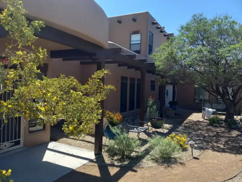 Stucco courtyard walls and portal with a tree and garden