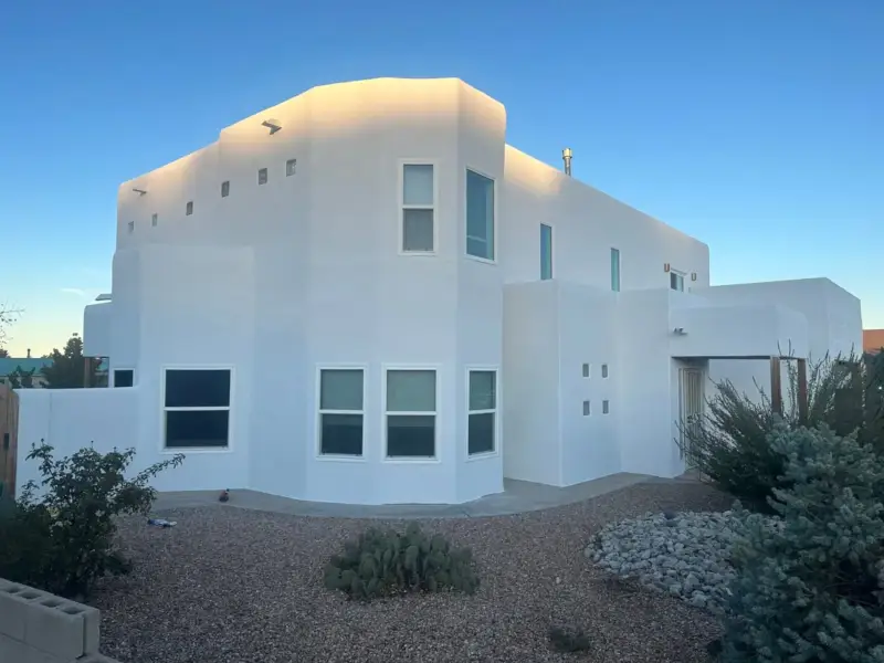 Two-story stucco house with an even white finish after patch repair