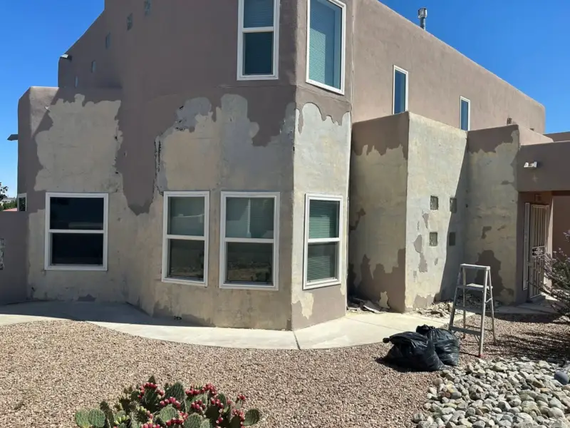Two-story stucco house with many gray patches before the finish coat