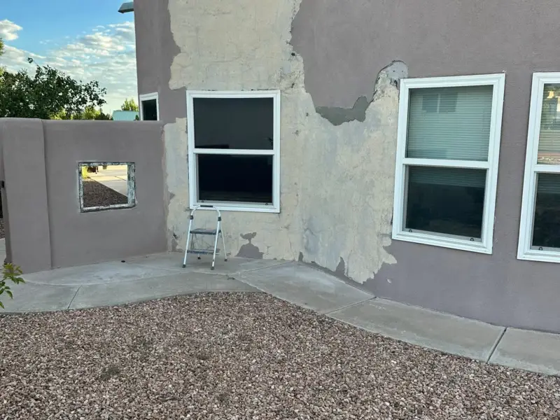 Two-story stucco wall with several gray patches waiting for the finish color coat