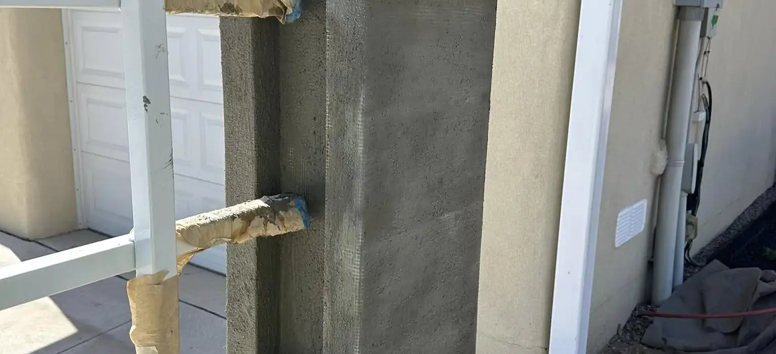 Stucco pillar with a formed cap beside a garage